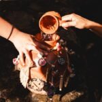 Hands pouring water into a traditional decorated Mexican clay pot during a ceremony in Uruapan, Michoacán, Mexico.